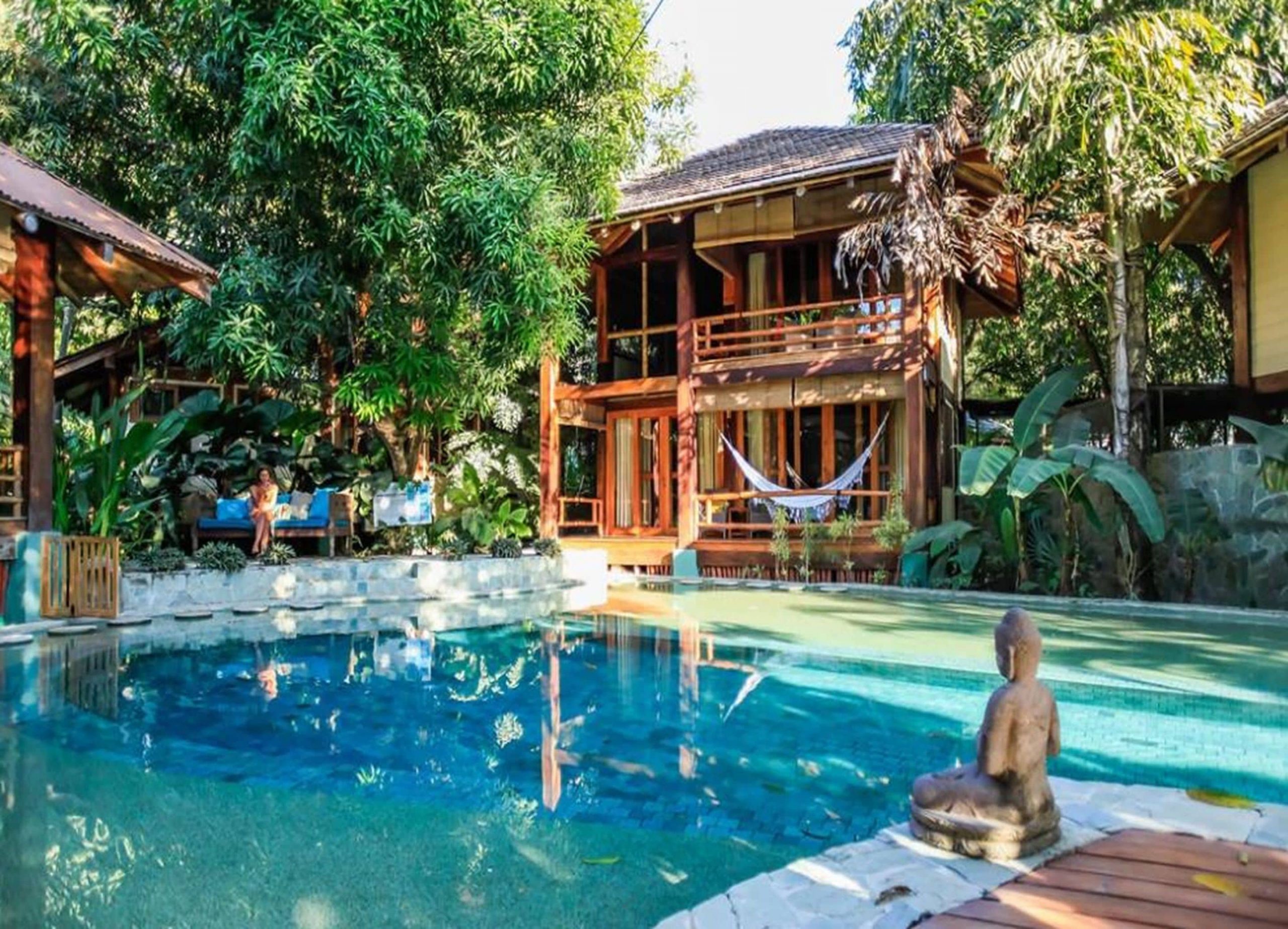 The outdoor pool area at Pranamar Villas and Yoga Retreat in Costa Rica with private villa, hammock, and ancient statue.