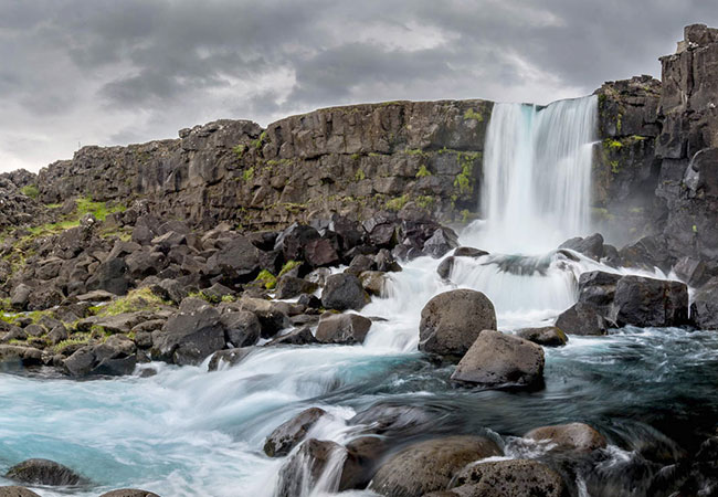 Waterfall running down rocks to river in Reykjavik