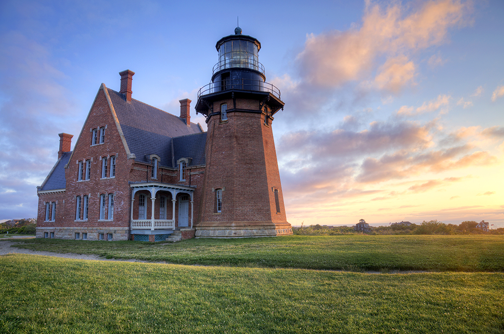 A lighthouse surrounded by lush green grass represents the nautical scenery on Block Island.