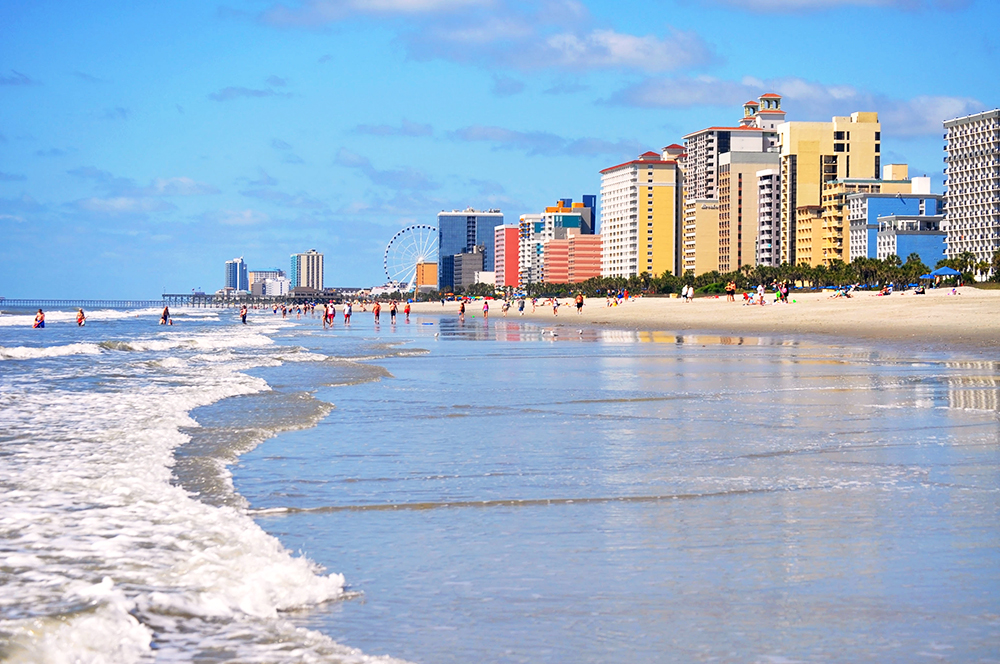 A sunny day on the shores of Myrtle Beach with hotels in the background.