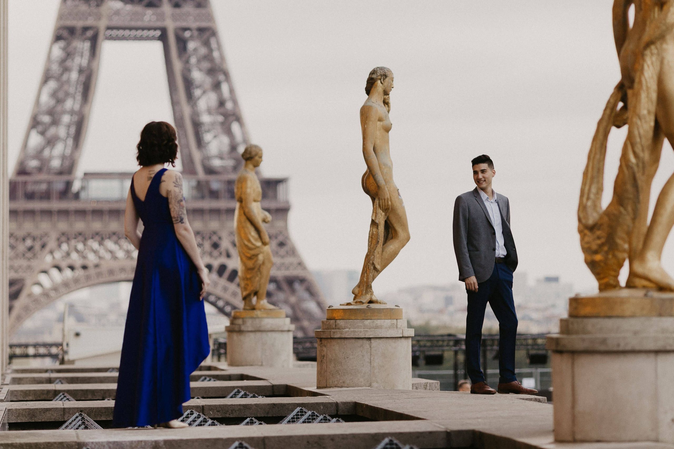 Romantic photo of a couple and statues with the Eiffle Tower in the background