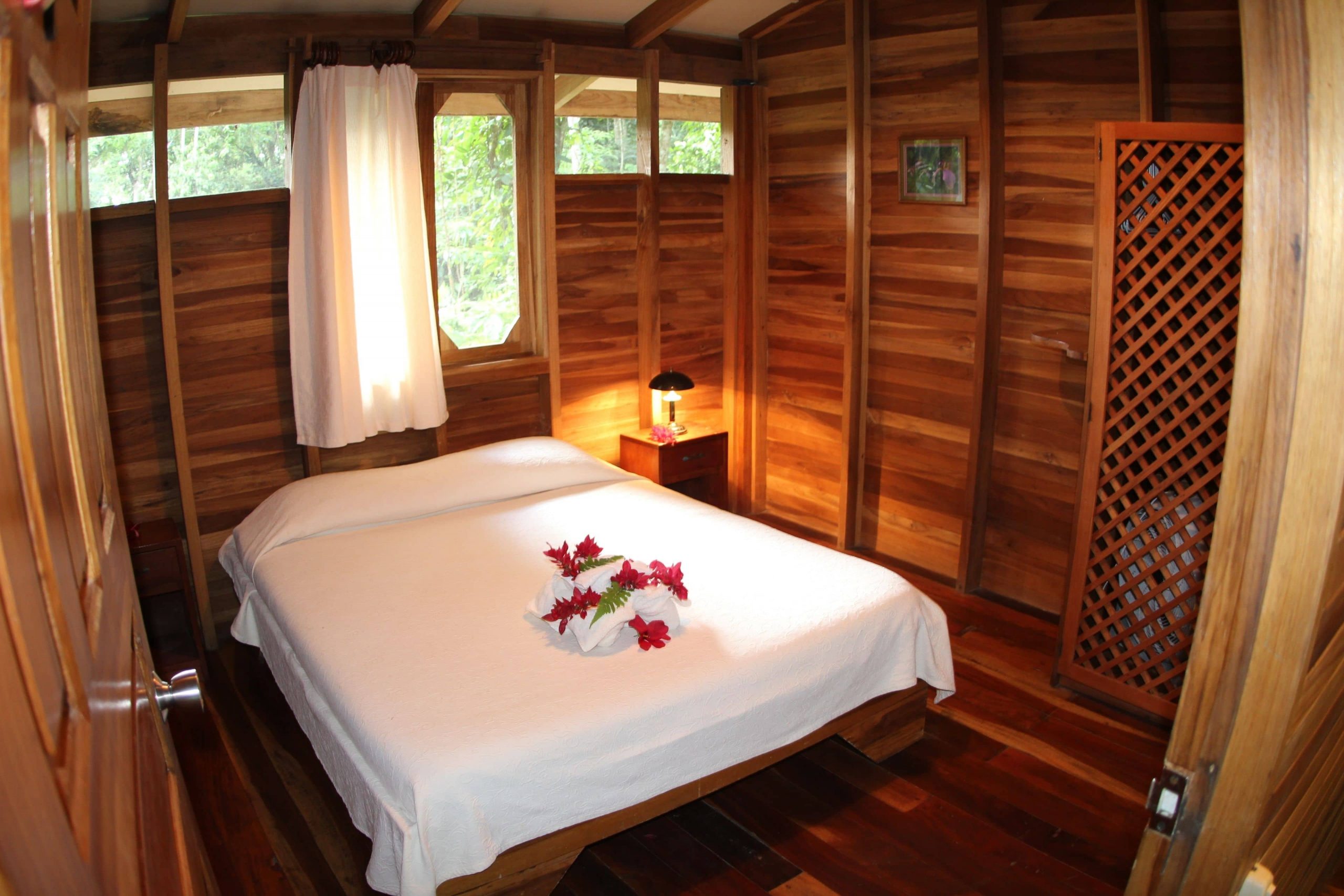 One of the options for guests to stay in when they choose a villa for their Samasati Yoga & Wellness Retreat with a king size bed, white linens, and beautiful wood panels in Costa Rica.