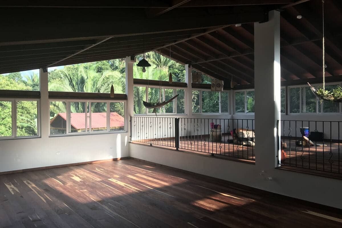 The large yoga studio with big windows looking out to the rainforest at a Sattva Land, Middlesex yoga retreat in Belize.