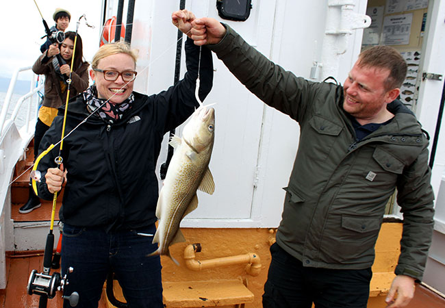 People hold up catch on fishing boat in Reykjavik