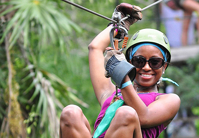 Woman smiling as she ziplines through jungle in Cancun