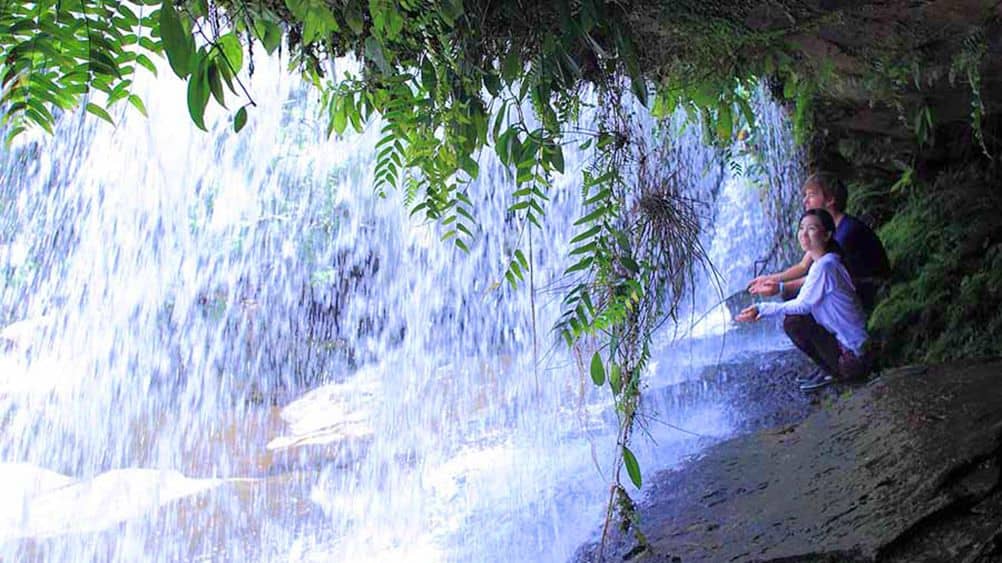 Sitting under a waterfall on a hiking tour in Japan