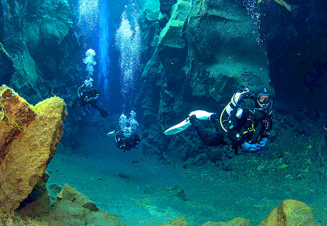 Scuba divers swim through clear waters in Reykjavik