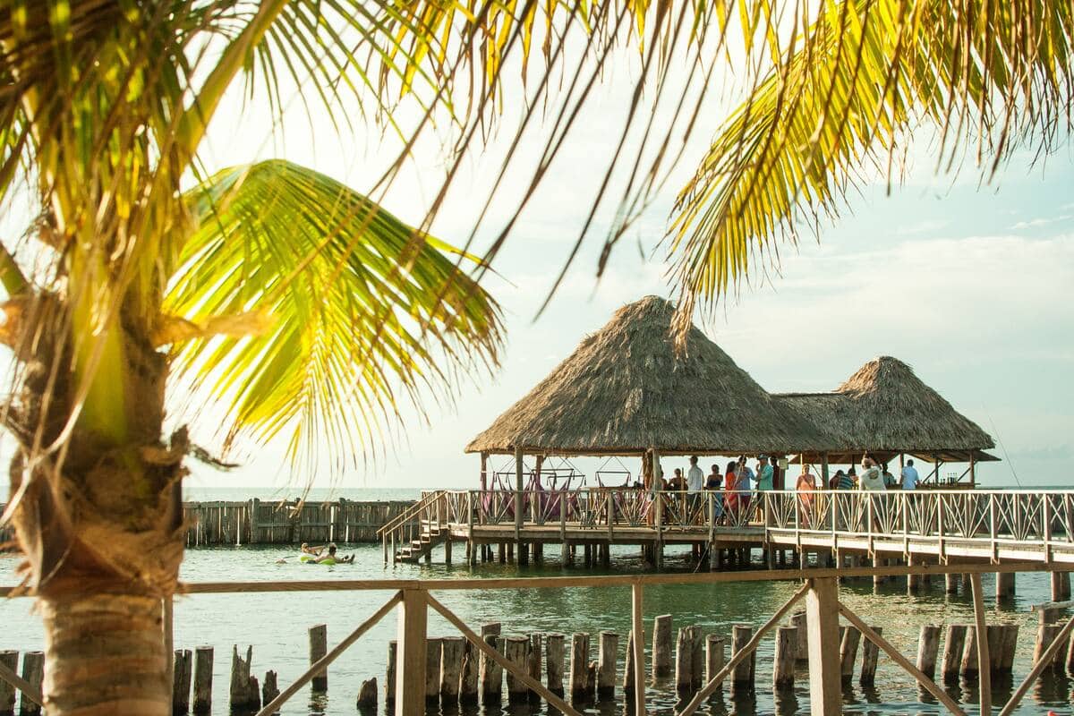Thatch Caye Yoga Retreat in Belize with a thatch roofed hut along a pier stretching out into crystal clear island waters.