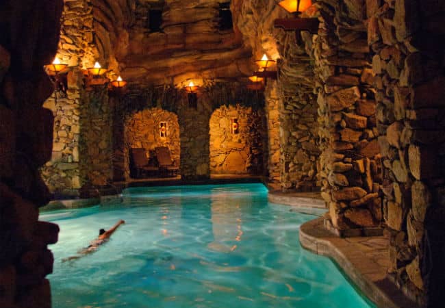 Woman swimming in the dimly lit cavern pool inside The Omni Grove Park Inn in Asheville, North Carolina.