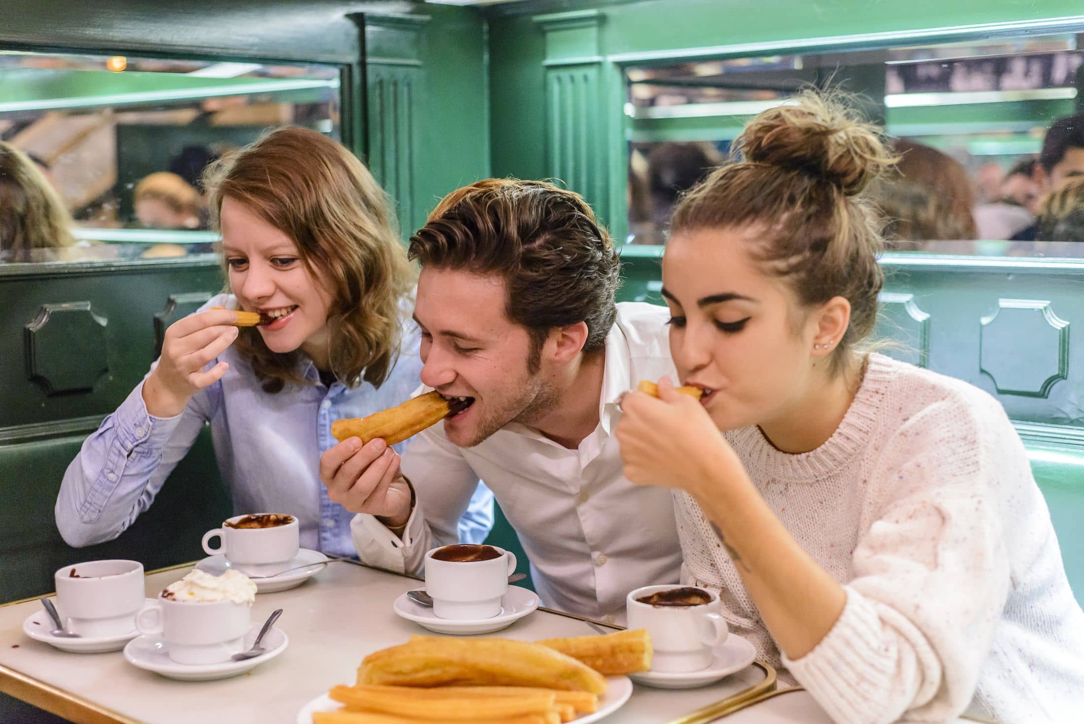 Three people eating chocolate and churros in Spain