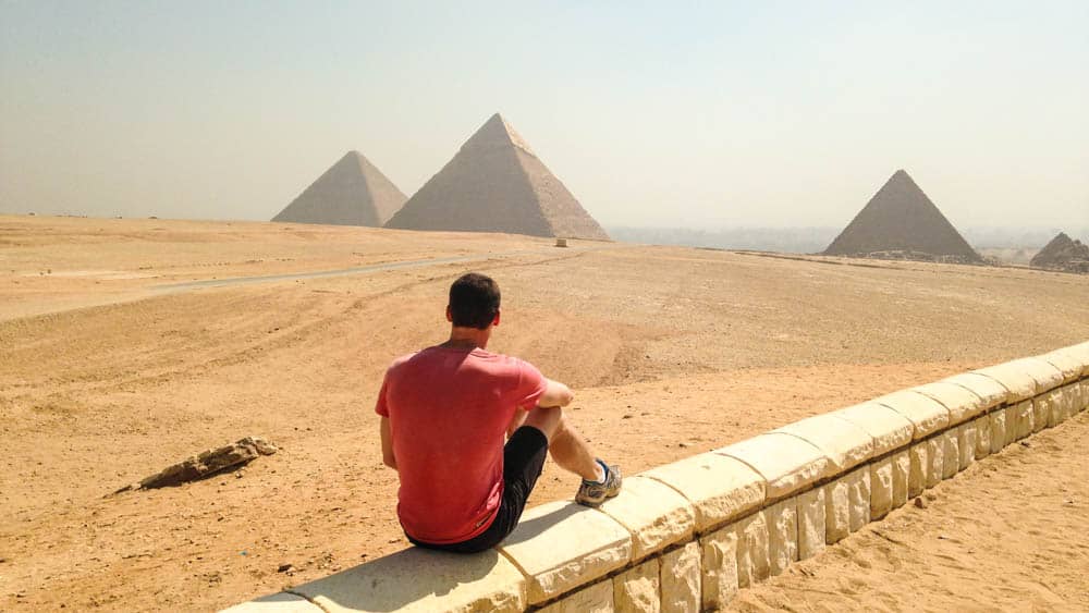 Tourist sitting and observing pyramids in the distance