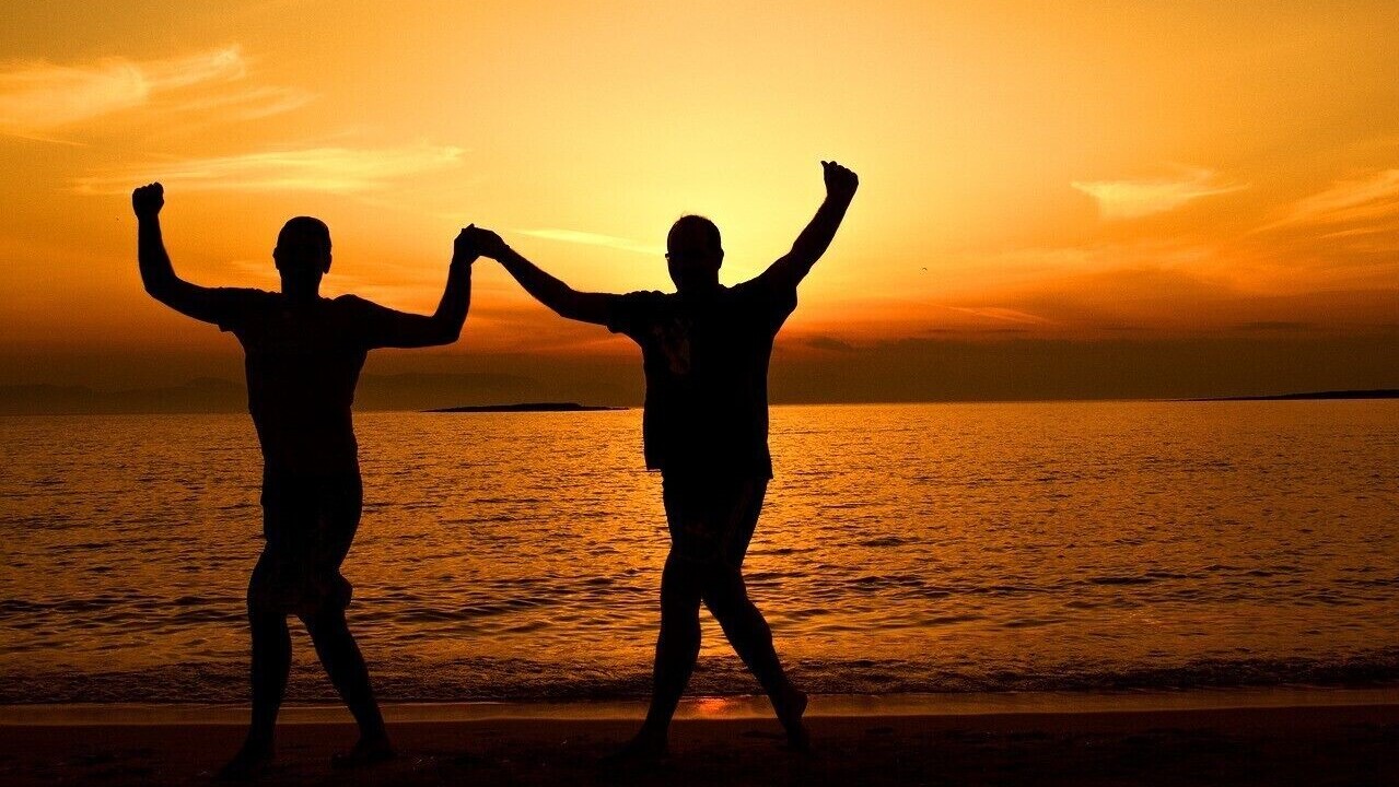 Two people on the beach doing a Greek dance