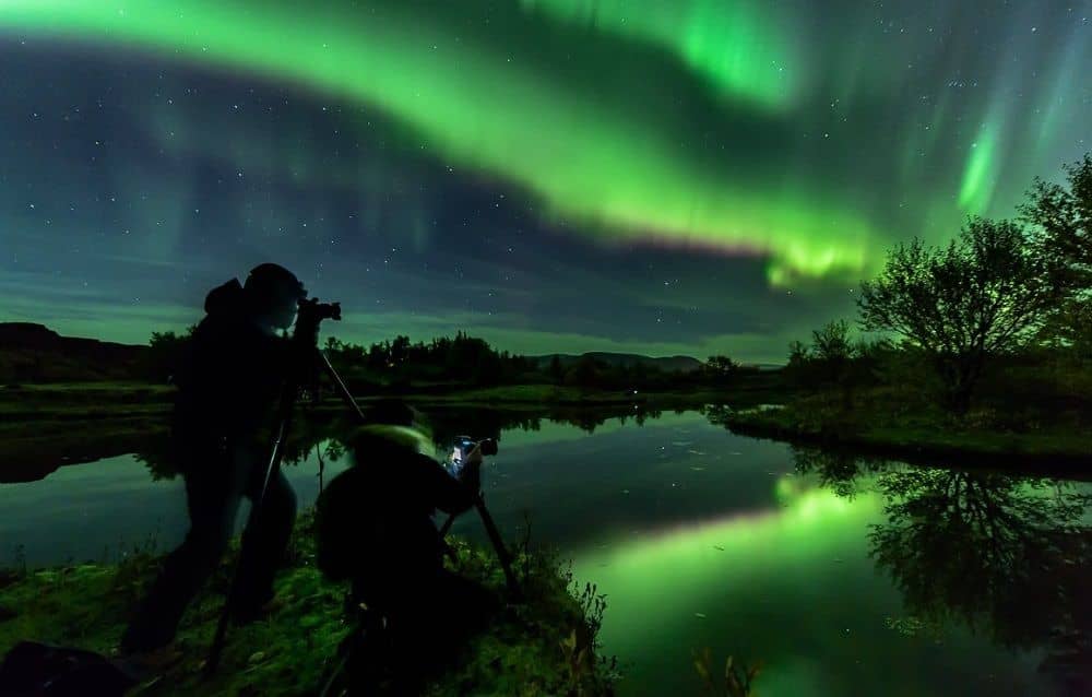 Two people taking pictures of the Northern Lights