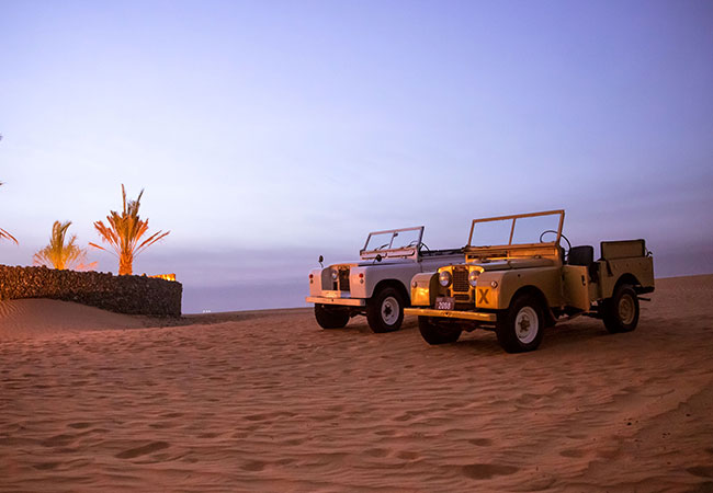 Two vintage Land Rovers in desert in Dubai