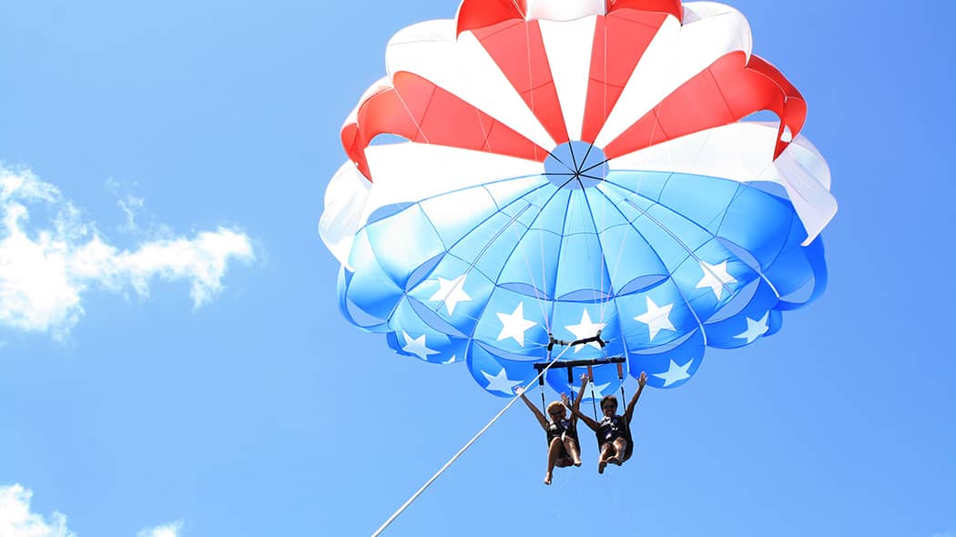 Two travelers parasail in Waikiki.