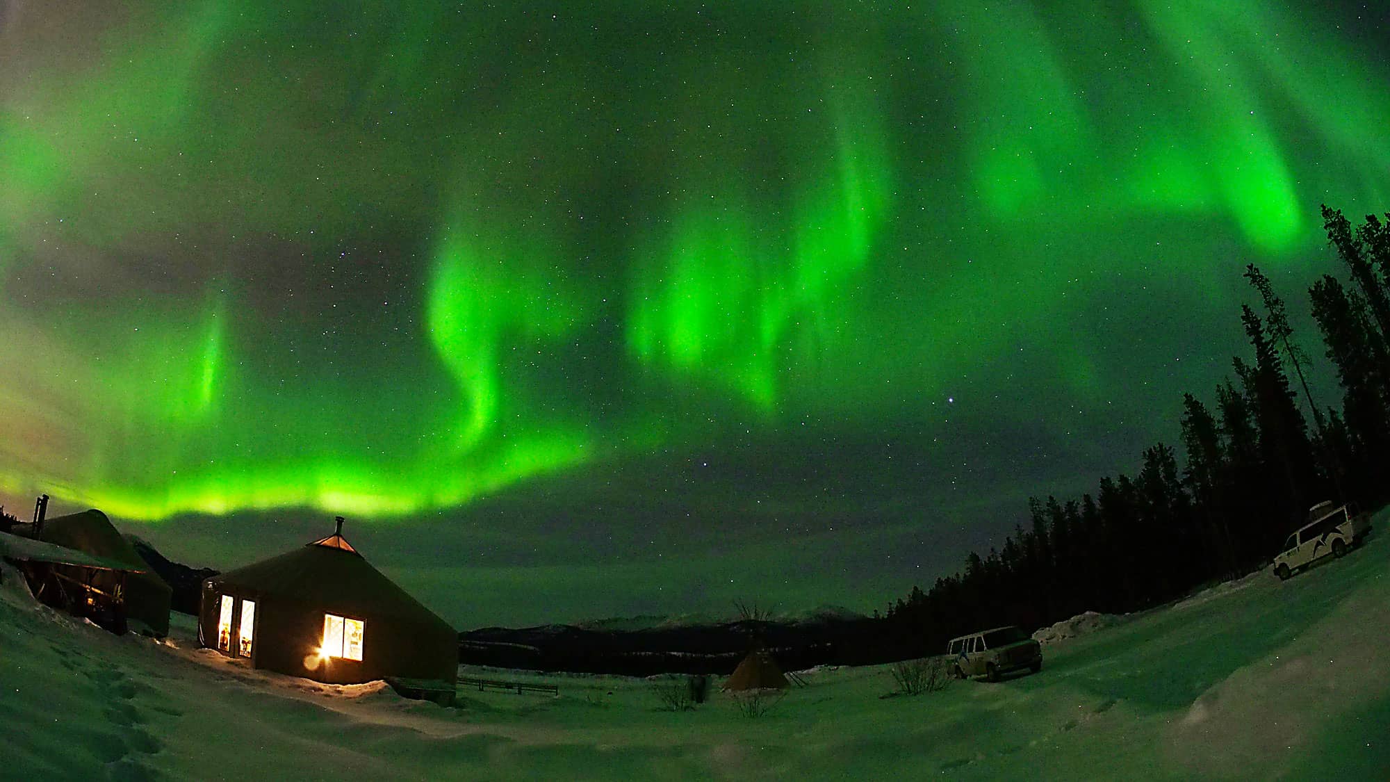 The aurora shimmers in the snow.