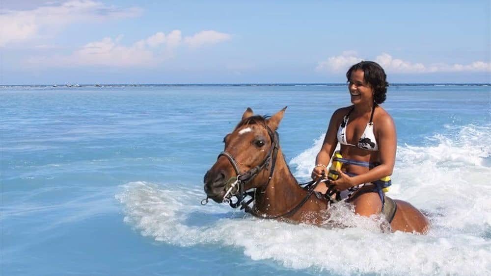 Woman riding a horse in the ocean in Jamaica