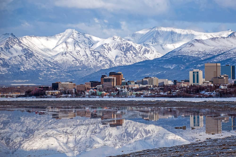 Snow covers the cityscape and mountains in Anchorage, which is one of the best places to vacation for Christmas.