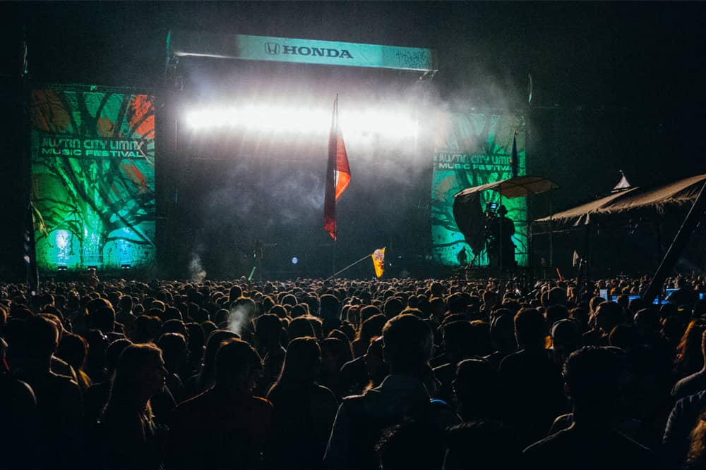 The Honda stage after dark and festival goers dressed in layers during Austin City Limits.