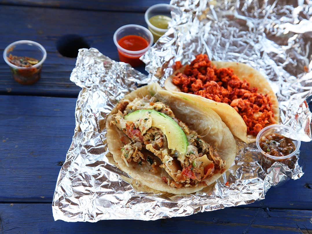 Two of Veracruz's fresh tacos, shown with four different types of sauces.