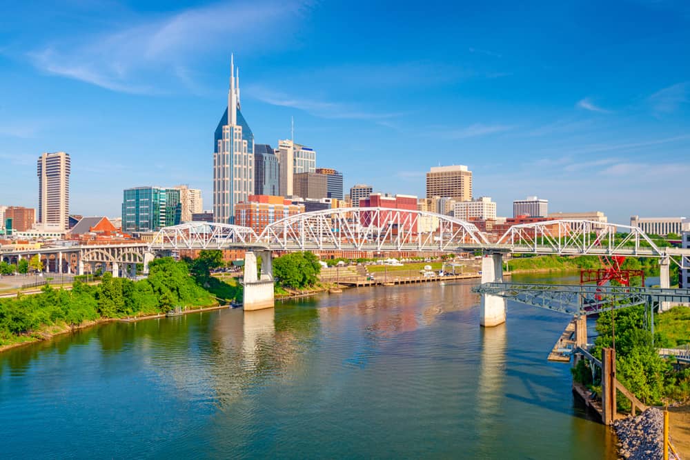 Downtown is the place to stay for your Nashville bachelor party Skyline of downtown Nashville on a sunny day with a blue sky and Cumberland River in the foreground