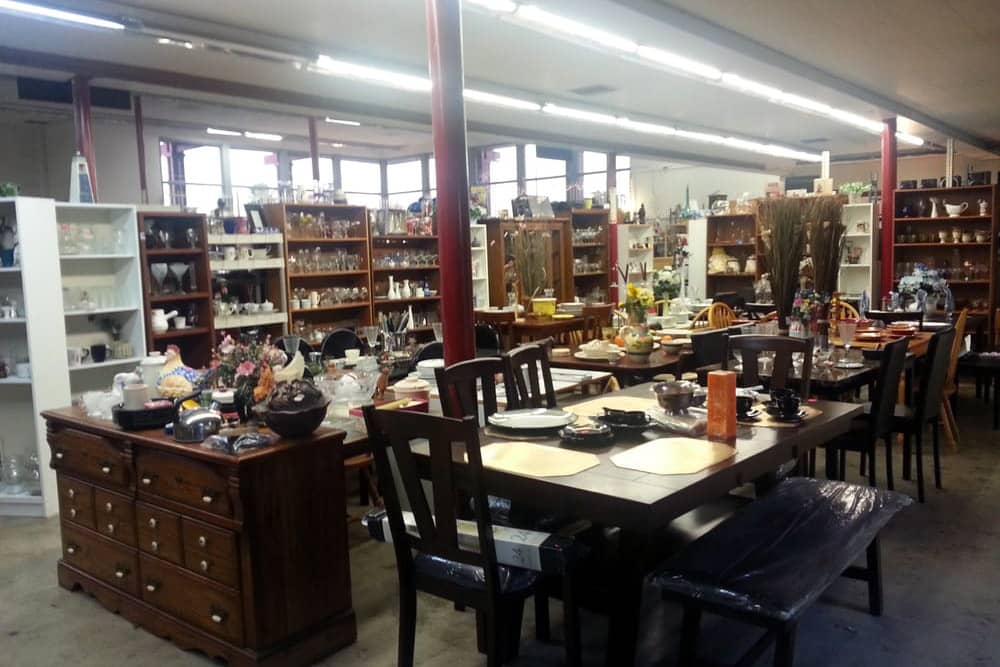 View of tables, chairs, and bookcases at Oki Doki Home Treasures, one of the best thrift stores in Anaheim.