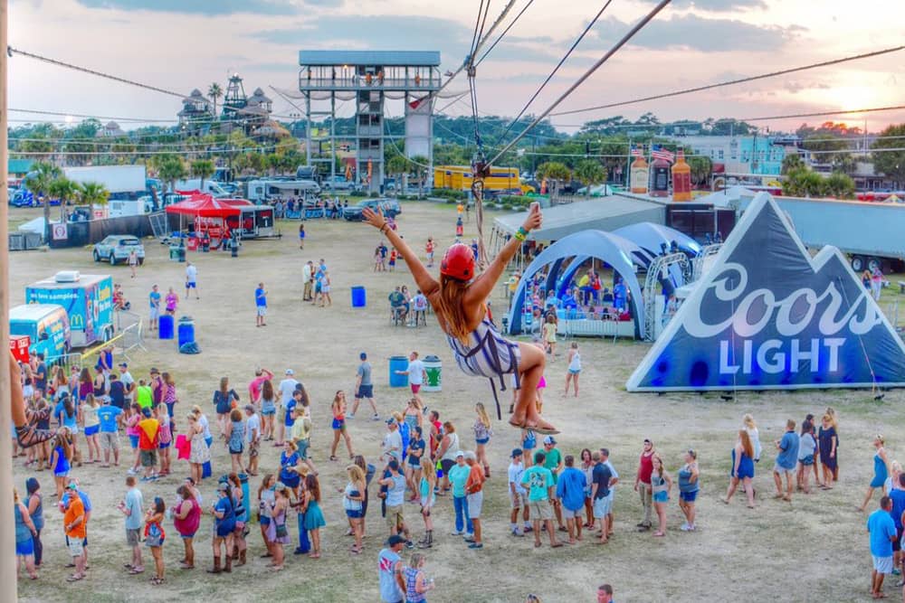 Woman goes down the zipline above the crowd at the Carolina Country Music Festival