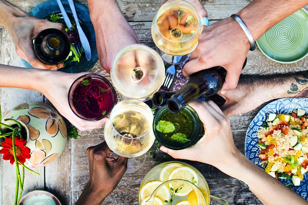 A group of hands cheers wine glasses at a winery in Napa.