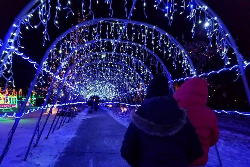 Two people stand under Christmas lights at night in Duluth, which is a great place to vacation to for Christmas.