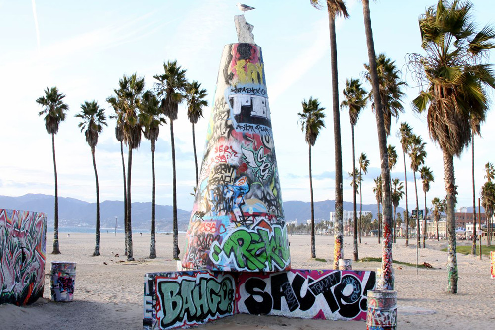 Colorful graffiti on concrete structures in front of palm trees on Venice Beach in Southern California. 