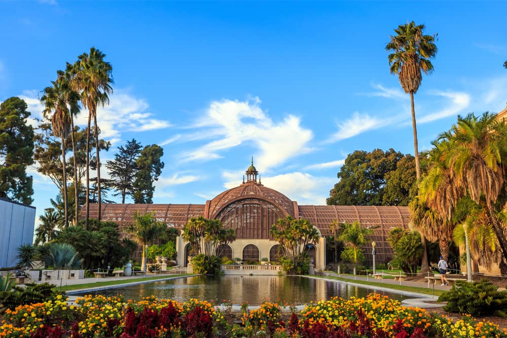 The grand entrance to the Balboa Botanical Building with a pond and flowers, which is a prime free attraction for kids in San Diego.