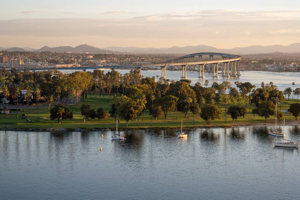 View of Coronado Island, a free attraction in San Diego, surrounded by water with the iconic bridge in the background.