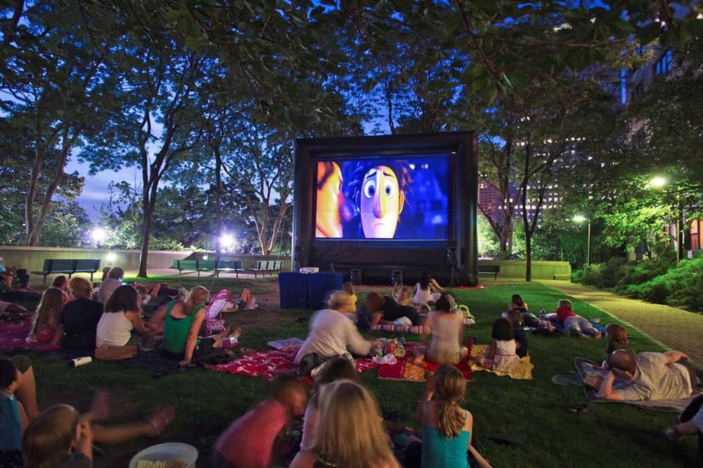 Families with kids watching summer movies in a park at dusk, one of the best free things to do in San Diego with kids