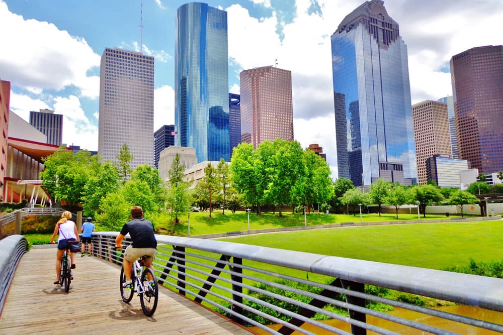 Family rides bikes across wooden bridge over Buffalo Bayou, a top free activities for kids in Houston