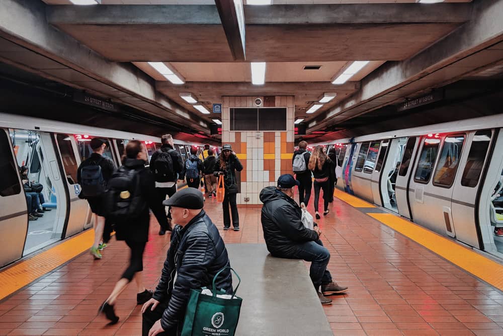 Travelers and commuters changing trains on an underground BART platform in San Francisco.