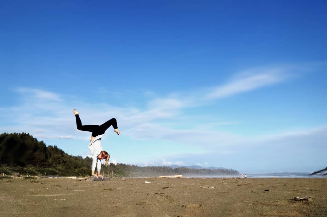 A woman doing a handstand on the beach for family vacation photos