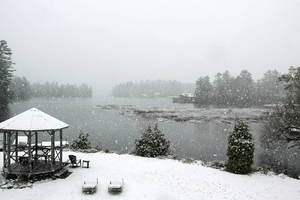 Snowflakes cover the ground and fall along the shoreline in Lake Placid, one of the best places to vacation for Christmas