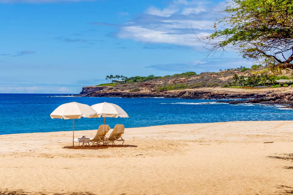 beach chairs and umbrellas for two by the ocean in lanai hawaii