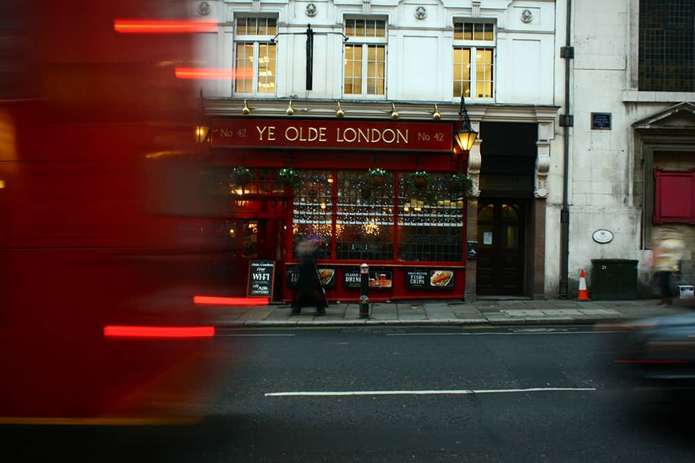 Motion blur of a red bus passing by the front of the Ye Old London Pub in London