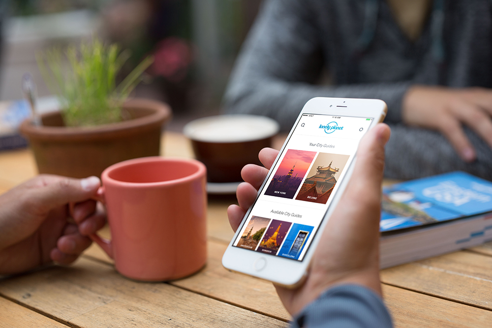 good travel apps person using lonley planet travel app on mobile phone