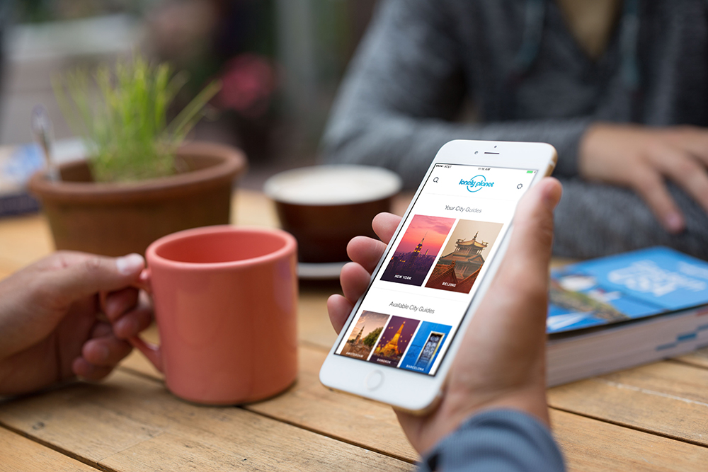 person using lonley planet travel app on mobile phone
