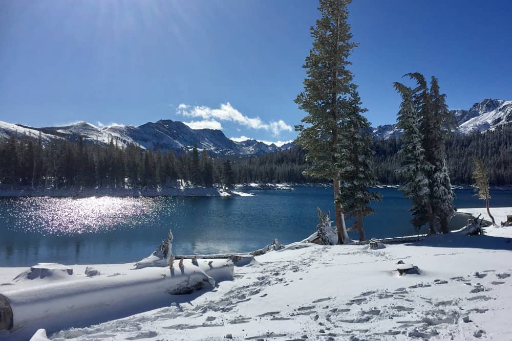 The sun shining down on a snow covered shoreline in Mammoth Lakes, a top place to visit on Christmas.