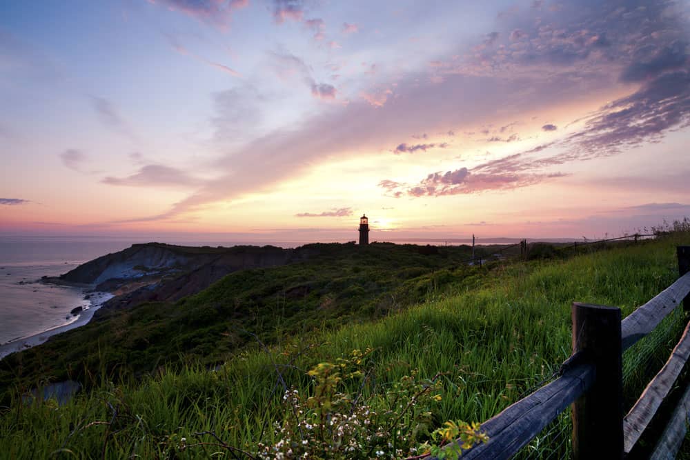 lighthouse in the distance on grassy cliff at sunset in Martha's Vineyard