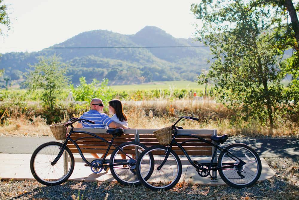 couple on bench in napa valley after bike ride through vineyards