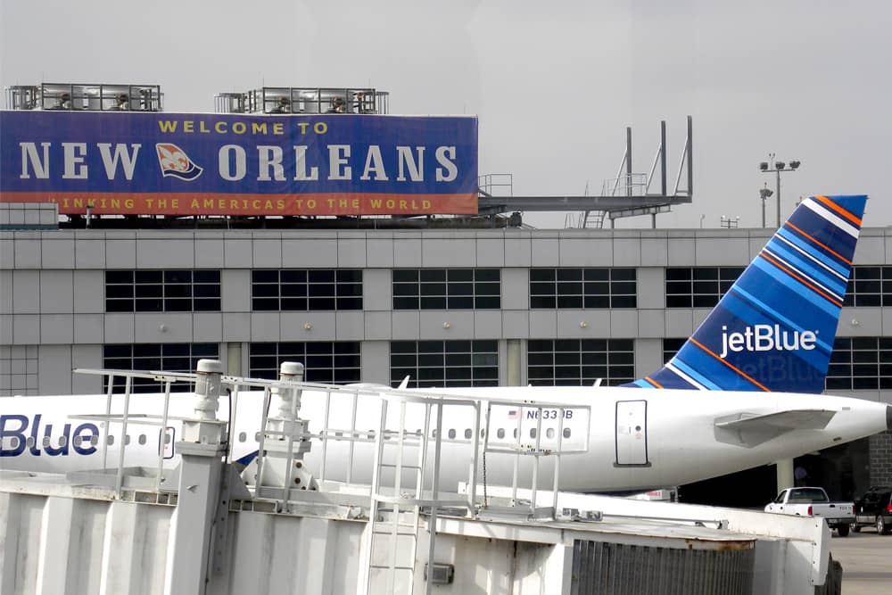 Airplane on the tarmac at Louis Armstrong New Orleans International Airport with a sign that reads "Welcome to New Orleans"