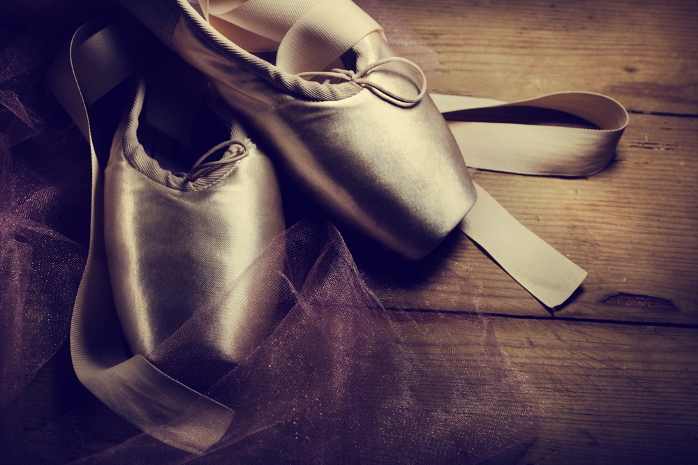 Satin ballet shoes on a wooden dance floor, part of the dance performances you'll see on a date at Phoenix First Friday.