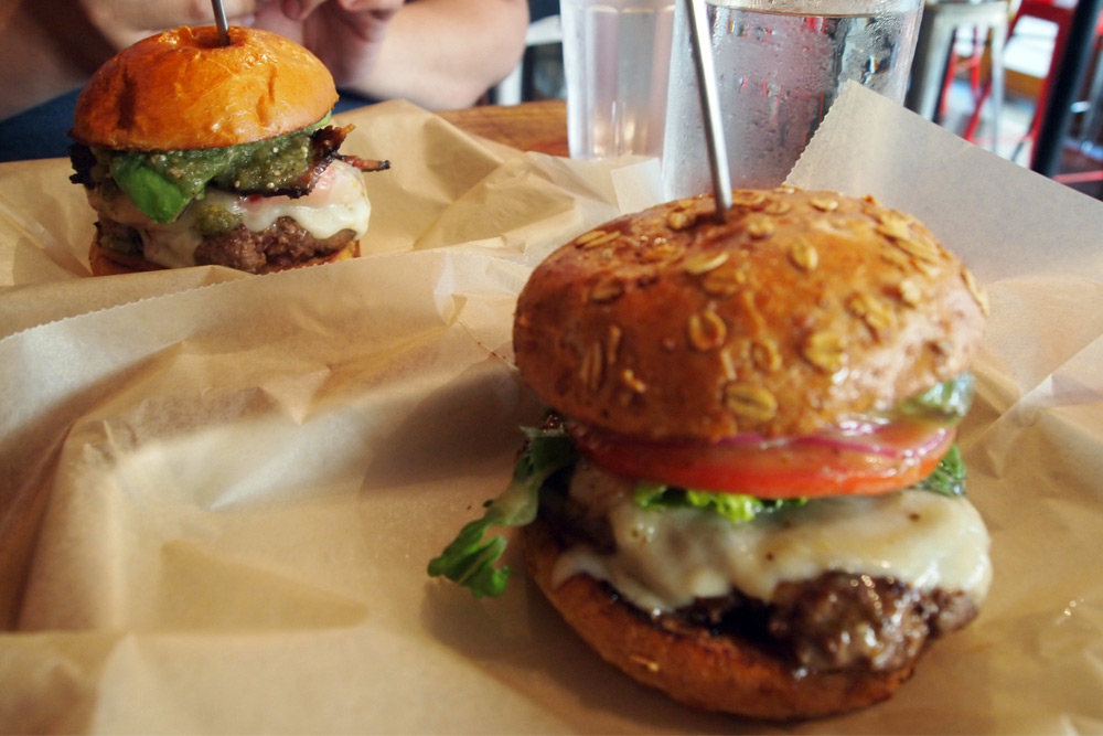 Two cheeseburgers at Bareburger, one served on a wholegrain bun and the other with bacon, avocado, and salsa—a delicious food option for New York Comic Con.