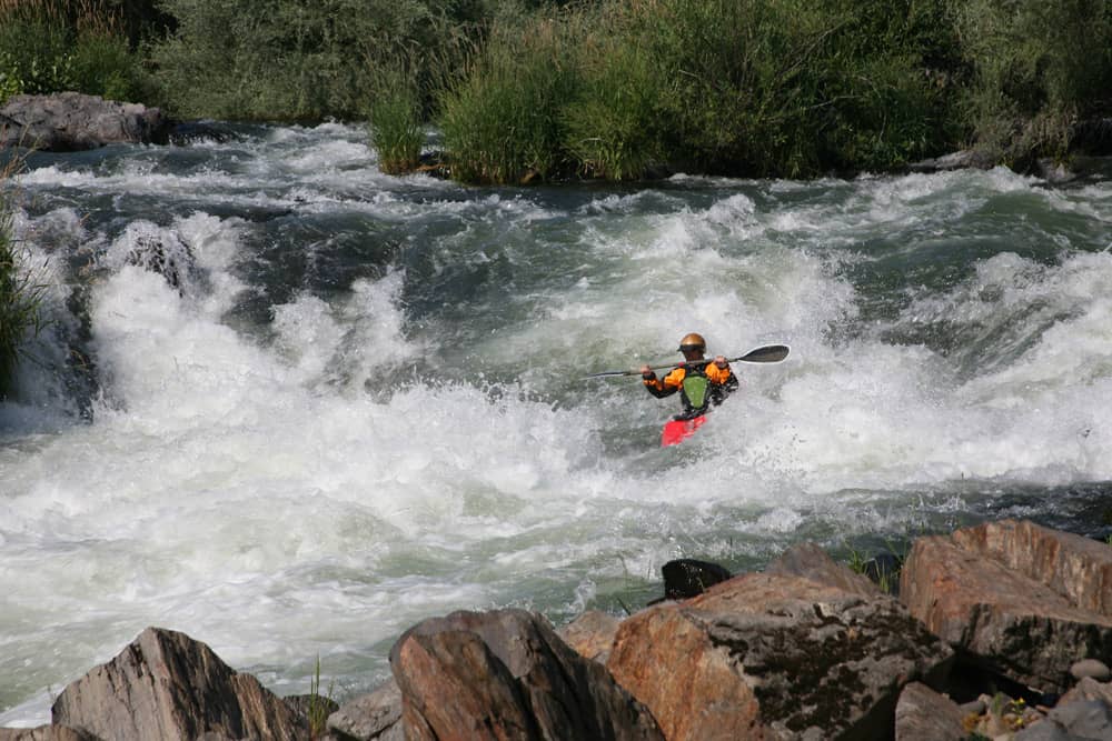 Kayaking Rogue River near Ashland, Oregon Kayaker paddling through the rapids on Rogue RIver—a fun thing to do during Oregon Shakespeare Festival.
