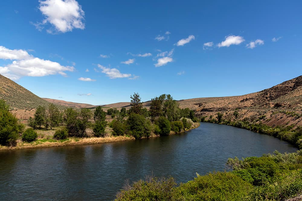 Calm river runs through tree-lined rolling hills