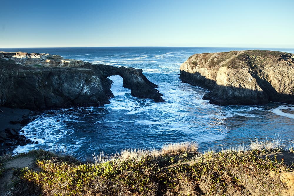 Natural rock bridge and waves lapping into a sea cove